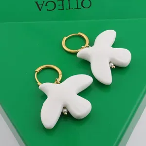 White ceramic dove earrings with gold hoops and pearl details, elegant jewelry accessory for women.