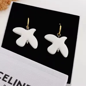White ceramic dove earrings detail view featuring gold-tone hoop and elegant pearl pendant