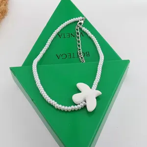 White pearl necklace featuring a ceramic dove pendant, elegant detail jewelry accessory.
