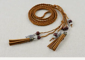 Detail view of ethnic style braided rope belt with wooden beads and tassels, brown decorative accessory.