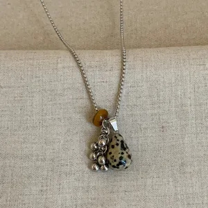 Detailopname van de vintage natuurstenen ketting met druppelvormige jaspis hanger en metalen druifbedel.