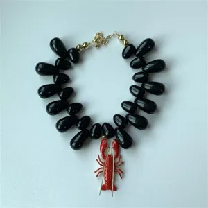 Collier ras du cou tendance avec perles en acrylique noir et pendentif homard rouge.