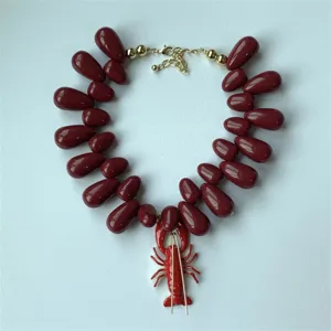 Vue détaillée du collier de perles en acrylique rouge avec pendentif homard unique.