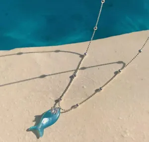Gros plan d'un collier de chaîne en perles argentées avec pendentif poisson vert menthe et zircon.