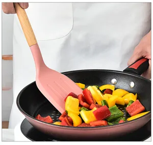 Detail shot showing a pink silicone spatula with wooden handle cooking colorful peppers.