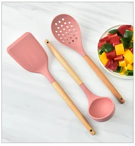 Detailed view of pink silicone kitchen utensil with natural wooden handle, heat resistant tool.