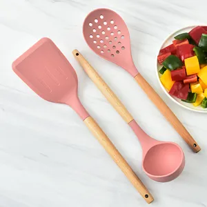 Pink silicone kitchen utensil set with wooden handles, spatulas and spoons for cooking.