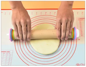 Detail view of adjustable wooden rolling pin with colorful thickness rings on silicone mat.