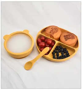 Silicone baby feeding set detail showing partitioned plate, ear bowl and spoon in yellow.