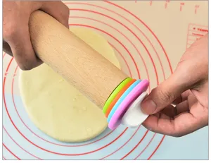 Detailed view of wooden rolling pin with colorful thickness rings and silicone baking mat.