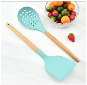 Silicone kitchen utensil detail showing slotted spoon and spatula with natural wooden handles.