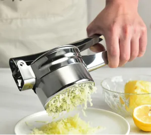 Presse-purée en acier inoxydable en gros plan montrant le mécanisme de pressage manuel.