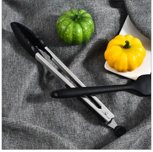 Stainless steel silicone kitchen tongs and spatula detail view for cooking food preparation.