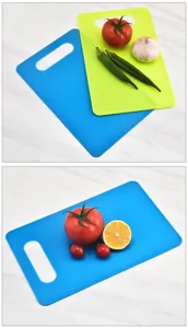 Detail view of plastic cutting boards in blue and green with fresh vegetables for kitchen use.