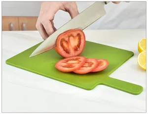 Gedetailleerd overzicht van een groen plastic snijplank in gebruik met verse tomaten.