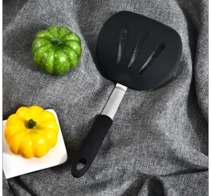 Detail view of a black silicone slotted spatula with metal handle on textured background.
