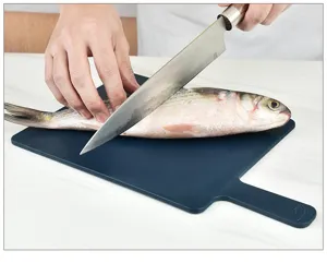 Gedetailleerd overzicht van donkerblauwe kunststof snijplank met mes en vis in keuken.