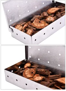 Stainless steel BBQ smoker box detail view showing perforated design and wood chips filling inside.