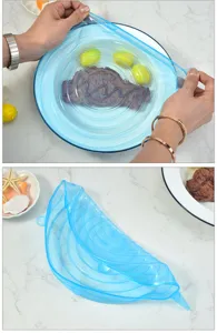 Dettaglio di coperchi elastici in silicone blu che mostrano elasticità su piatti e ciotole.