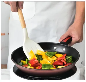 Detalle espátula de silicona con mango de madera, utensilio de cocina para sartén antiadherente.