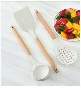 Detalle del juego de utensilios de cocina de silicona con espátula, espumadera y cucharón de madera.