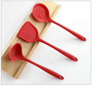 Vista di dettaglio ravvicinata di utensili da cucina in silicone rosso su supporto di legno.