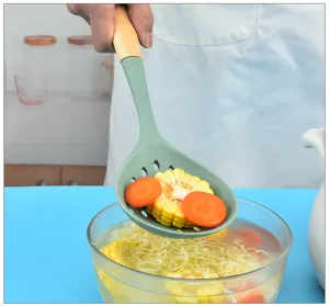 Detail shot of green silicone slotted spoon with wooden handle scooping food from bowl.