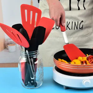Silicone kitchen utensil set with spatula, spoon, tongs and glass storage jar for cooking.