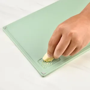Multifunctionele groene snijplank met ingebouwde rasp voor dagelijks koken thuis.