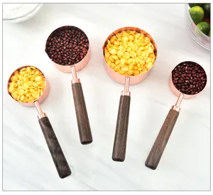 Detailed close-up of rose gold measuring spoons with walnut handles in kitchen setting.
