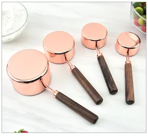 Detailed view of rose gold measuring cups with wooden handles for baking and kitchen use.