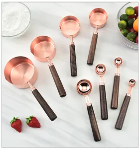 Rose gold copper plated measuring spoons and cups set with walnut wooden handles for baking.