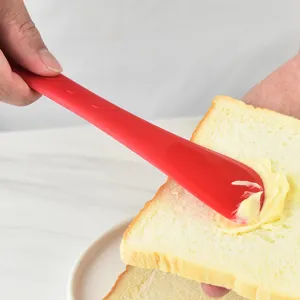 Rode siliconen dubbelkoppige spatel voor het smeren van boter en jam op brood, bakgereedschap.