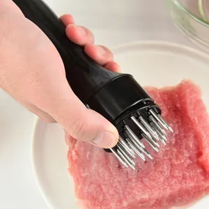 Stainless steel meat tenderizer tool with sharp needles for kitchen cooking and beef steak prep.