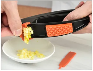 Close-up of manual plastic garlic press tool in action, showing efficient garlic mincing.