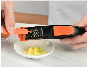Close-up of the black and orange plastic garlic press showing the pressing structure detail.