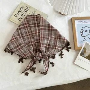 Nahaufnahme des braunen karierten Dreieckschals mit niedlichen Anhängern für modisches Styling.