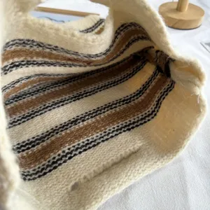 Gros plan de la sacoche à rayures en tricot montrant une texture douce et un style cosy.
