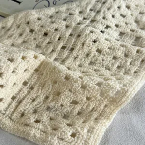Detailopname van beige handgemaakte holle gehaakte gebreide stof, fijne textuur.