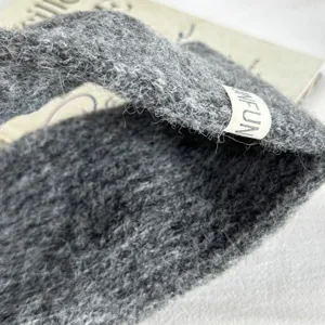 Close-up detail of dark grey fuzzy knitted hairband, soft winter wool headband texture.