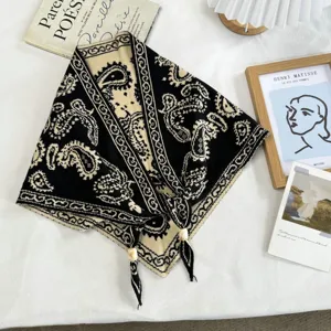 Detalle de bufanda triangular de punto paisley, negro y beige retro con elegantes borlas de cuentas.