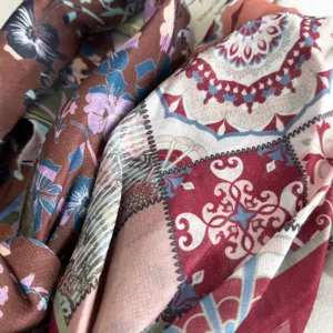 Close-up detail of retro floral printed silk scarf, elegant geometric patchwork design.