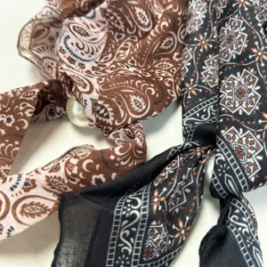 Retro printed silk scarf detail with pearl accessory, fashion neckerchief close-up.