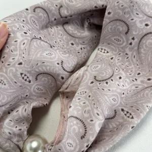Detail view of the pink retro paisley small silk scarf with a pearl accessory close-up texture.