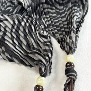 Close-up detail of retro pleated textured triangular headscarf with beaded tassel accents.