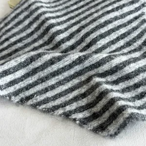 Close-up of black and grey striped knitted fabric detail, soft and cozy winter scarf texture.