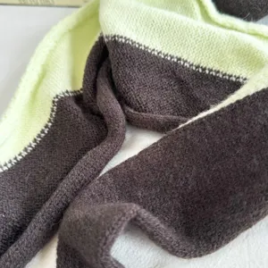 Detailed view of the color-blocked knitted scarf, soft texture, warm and stylish neck warmer.