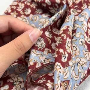 Detailed close-up view of the red and blue floral pattern silk scarf fabric and hem edge.