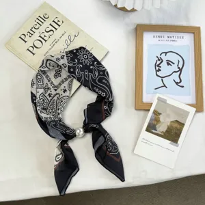 Detail view of the paisley silk scarf featuring a pearl buckle and stylish black white design.