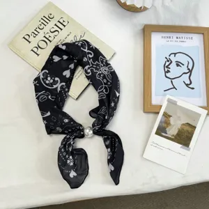 Detailed view of black and white paisley silk scarf with elegant pearl buckle necklace decoration.